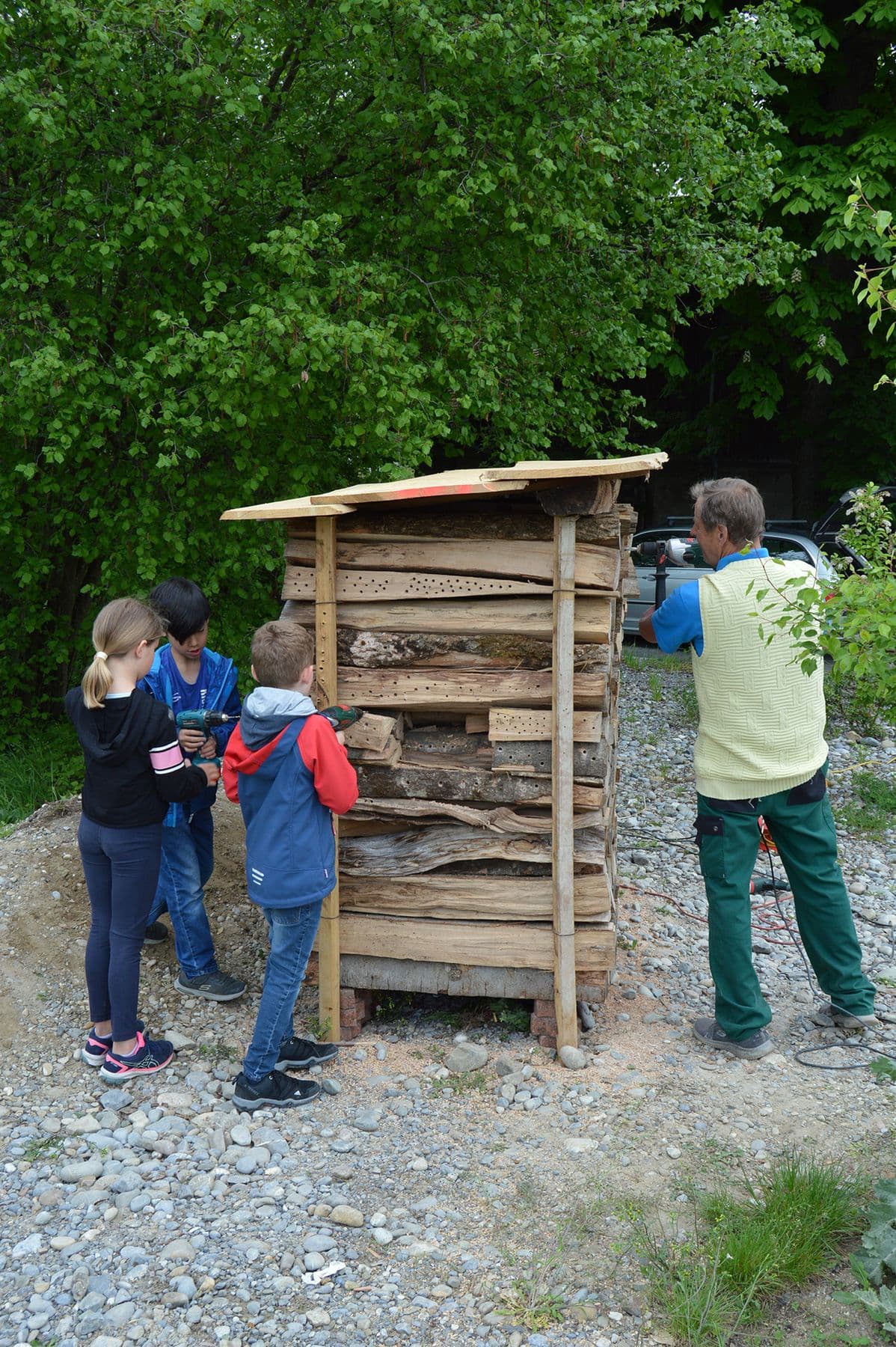 Schüler:innen und ein Lehrer bauen eine Nisthilfe für Mauerbienen und andere Insekten