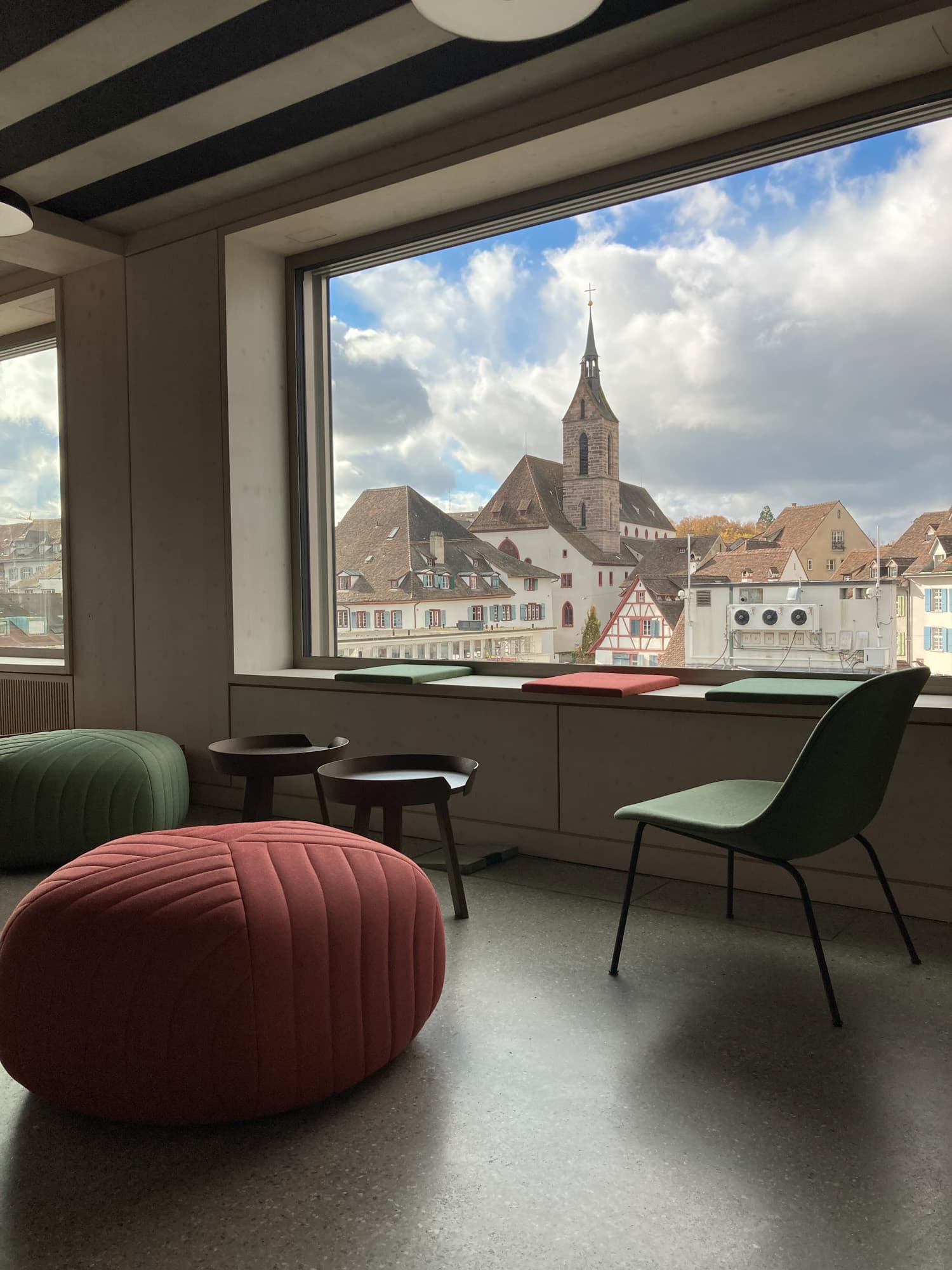 Sitzpolster und Stühle vor einem Panorama-Fenster mit Blick auf Basel