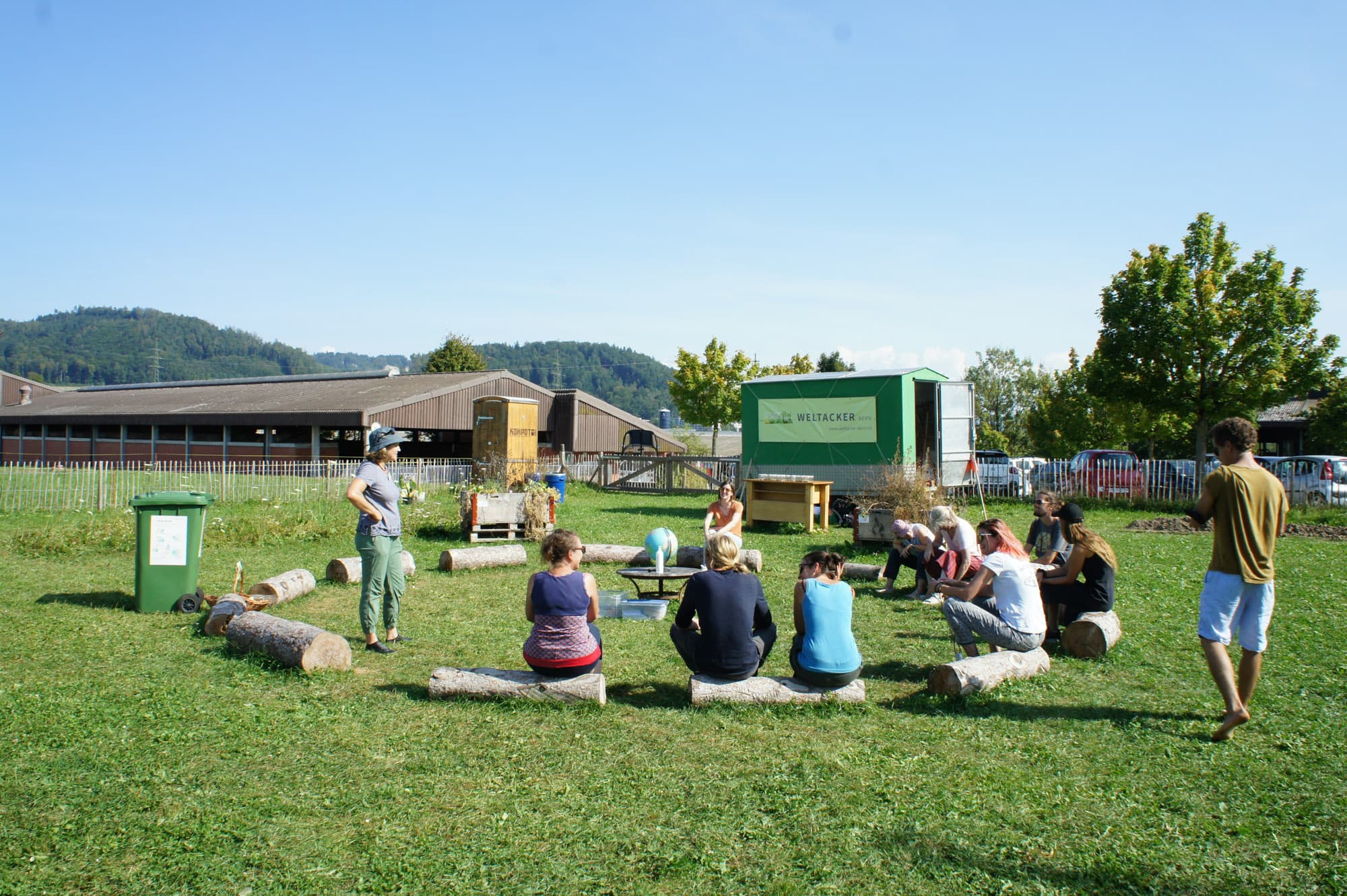 Erwachsene sitzen auf einer Wiese im Kreis.